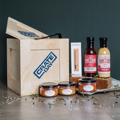 Wooden crate with BBQ spices, suaces and meat thermometer